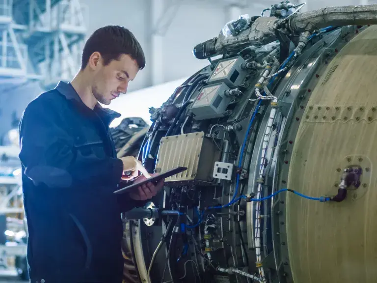 Aircraft Maintenance Mechanic Inspecting and Working on Airplane Jet Engine in Hangar